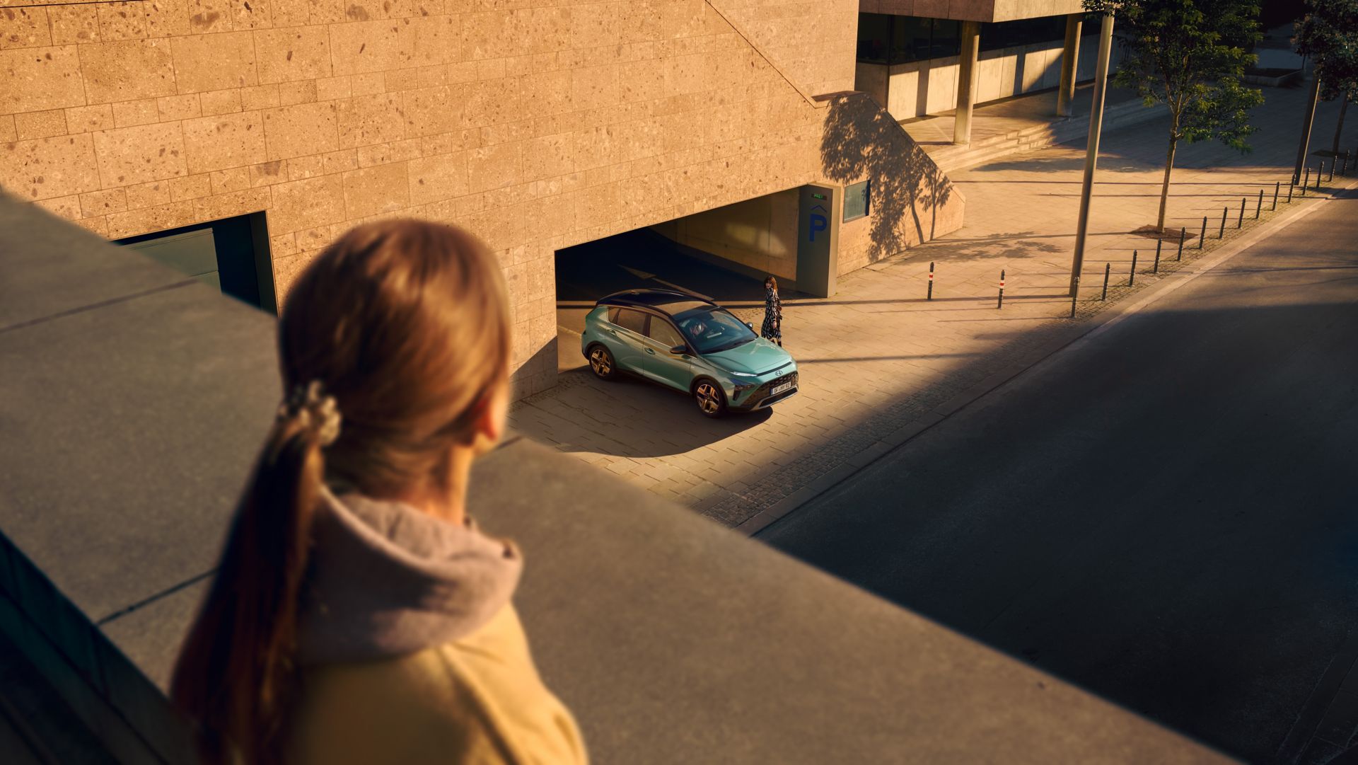 Topview of the all-new Hyundai BAYON compact crossover SUV driving out of a parking garage.