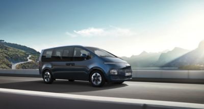 The all-new Hyundai STARIA driving on a highway seen from the front.