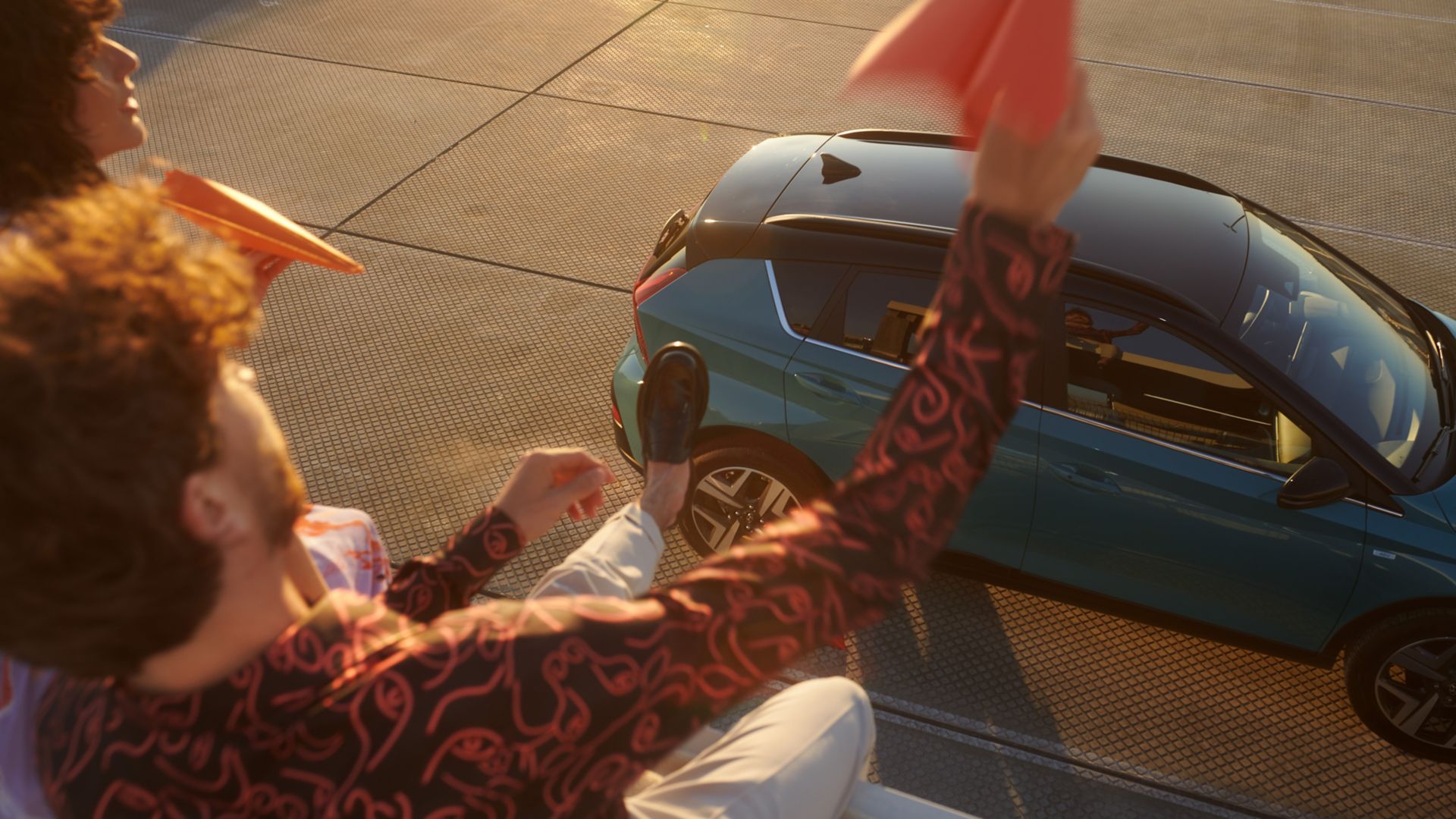 Two people throwing paper planes over the all-new Hyundai BAYON compact crossover SUV.